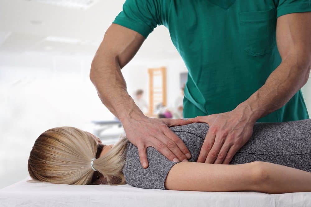 A practitioner's hands working on the muscles of a patient's back.