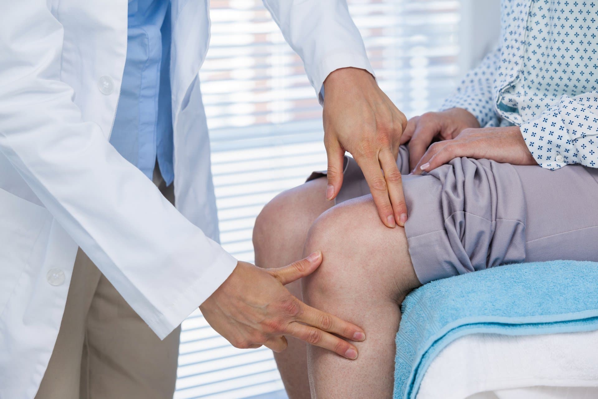 A clinician examining a patient's knee.
