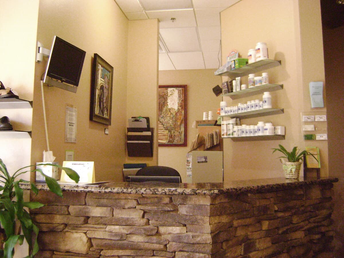 The LifeCare Chiropractic front desk — a stacked-stone reception counter with supplement shelves and framed artwork behind it.